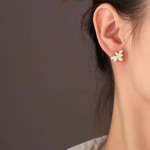 Elegant golden bee stud earring with micro-pave zircons shown on a model's ear