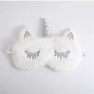 Detailed macro shot of white plush unicorn sleep mask featuring silver glitter horn and ears