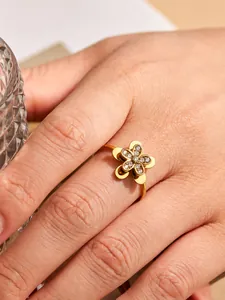 Detailed view of a gold-tone flower ring with sparkling zircon inlays on finger.