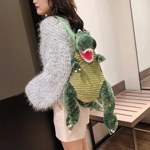 Primo piano di una modella che indossa uno zaino di peluche T-Rex verde per bambini in negozio.