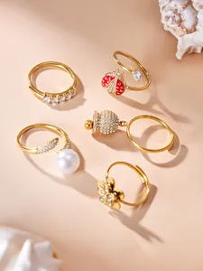 Detailed macro view of gold zircon rings featuring ladybug, flower, and pearl motifs.