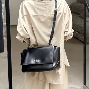 Minimalist black genuine leather messenger bag with silver lock and adjustable strap.