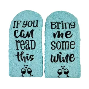 Detailed view of light blue coral fleece socks with funny Bring me some wine non-slip text