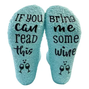 Close-up of fluffy coral fleece socks with humorous wine-themed anti-slip lettering