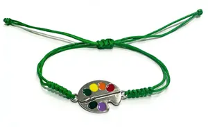Close-up of green hand-woven wax cord bracelet with colorful paint palette charm