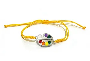 Detail of handmade yellow braided cord bracelet with alloy artist palette charm