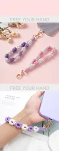 Detailed macro view of hand-woven daisy phone lanyard wrist strap in purple and white tones