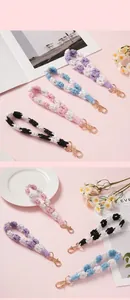 Detailed view of hand-woven daisy flower lanyards in various pastel colors with gold clasps.