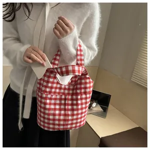 Red and white checkered gingham canvas tote bag held by a person showing its size