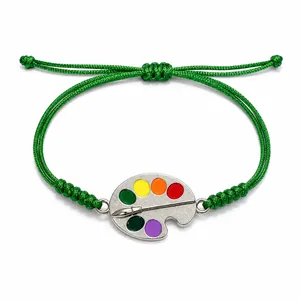 Handmade green wax cord woven bracelet featuring a colorful artist palette and brush charm