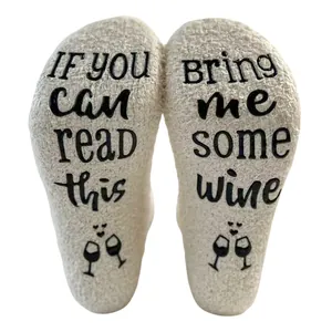 Close-up of fuzzy coral fleece floor socks with non-slip wine quote text on soles