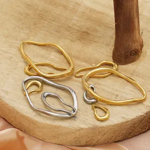 Detailed close-up of irregular wavy oval frame pendants in 18k gold and silver plating