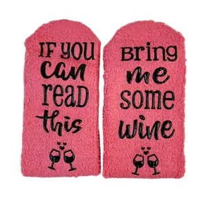 Macro view of pink coral fleece socks featuring 'Bring Me Some Wine' non-slip sole