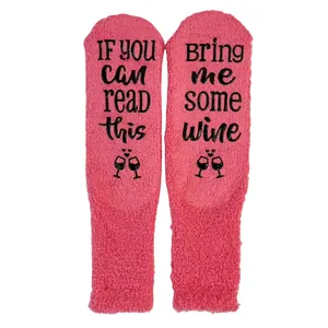 Close-up detail of pink coral fleece socks with anti-slip 'Bring me wine' text design
