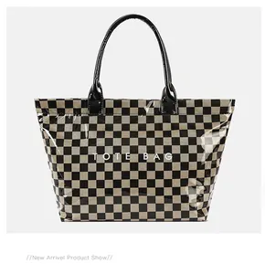 Detail view of a checkerboard tote bag with a transparent PVC outer layer and black straps.