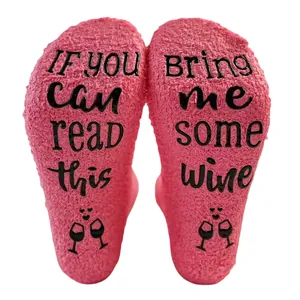 Close-up of pink coral fleece socks with 'Bring me some wine' anti-slip soles