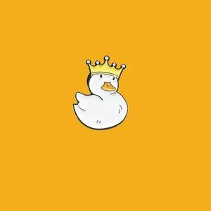 Close-up of cute white enamel duck pin wearing a yellow crown on a yellow background