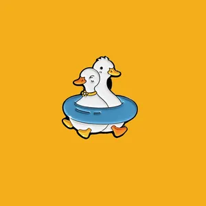 Detailed close-up of a cute metal enamel pin featuring two white ducks in a blue swim ring.