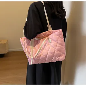 Gros plan d'un sac en coton matelassé rose porté à l'épaule par un mannequin chic