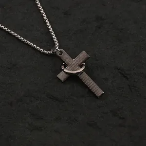 Detailed view of stainless steel cross pendant with ring on dark textured background