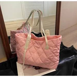 Sac fourre-tout matelassé rose avec bretelles blanches sur un miroir et soie noire.