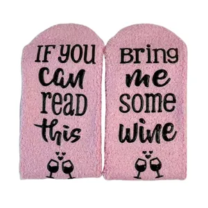 Detail of pink coral fleece socks with anti-slip 'Bring me some wine' lettering