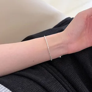 Close-up detail of a minimalist S925 broken silver chain bracelet on a woman's wrist