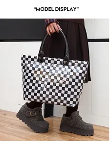 Detailed view of fashionable checkerboard PVC tote bag held by model in casual outfit