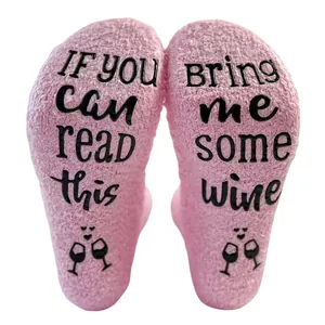 Detailed view of pink coral fleece socks with 'Bring Me Some Wine' anti-slip rubber text