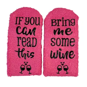 Detail view of pink coral fleece socks with 'Bring Me Some Wine' non-slip lettering.