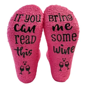 Detailed macro view of pink fuzzy floor socks with non-slip Bring Me Wine text and icons