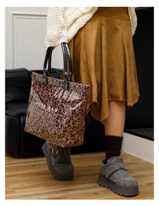 Leopard print PVC tote bag with white text held by a model in casual outfit