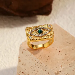 Detail view of vintage gold evil eye ring with green stone inlay and hammered texture