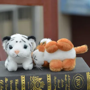 Paire de jolis pendentifs en peluche tigre blanc et orange sur un livre classique
