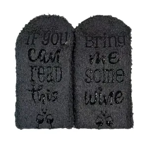 Detailed close-up of fuzzy coral fleece floor socks with non-slip 'Bring me wine' text