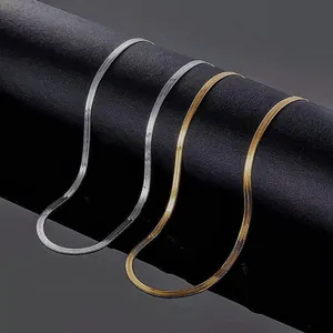 Close-up of minimalist gold and silver stainless steel herringbone snake chain necklaces.