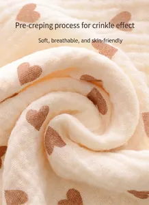 Gros plan sur le tissu de l'emmaillotage en gaze de coton avec motif cœurs marron.