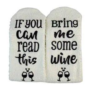 Macro view of coral fleece fuzzy socks with non-slip 'Bring me some wine' lettering