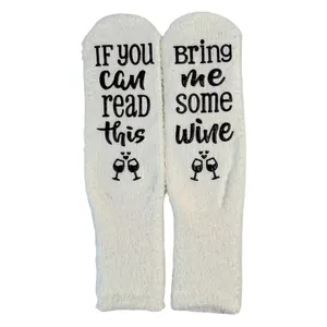 Close-up of fuzzy coral fleece floor socks with "Bring me some wine" non-slip text.
