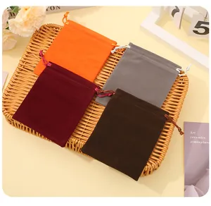 Detailed view of colorful velvet drawstring pouches for jewelry storage on a woven tray.