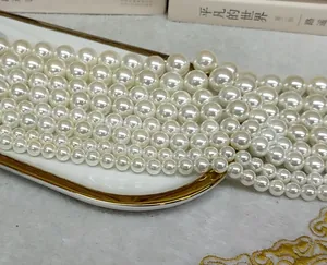 Close-up of high luster white imitation pearl beads in various sizes for DIY jewelry.