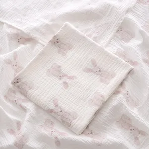 Vue détaillée du motif lapin rose sur une couverture en mousseline de coton blanc