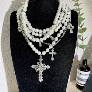 Multi-layer pearl necklace with ornate silver cross pendants on a black display bust