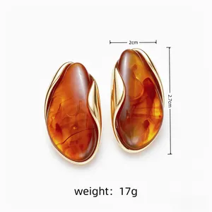 Close-up of irregular amber resin stud earrings showing 2cm width and 17g weight