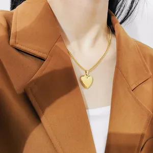 Close-up van een gouden hart hanger ketting van roestvrij staal gedragen door een model in blazer