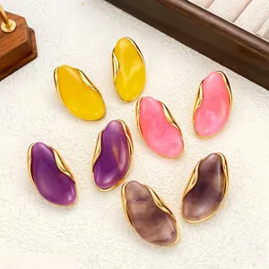 Close-up of irregular resin stud earrings in assorted vibrant colors with gold trim