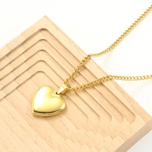 Detailopname van een gouden hartjesketting op een houten dienblad.