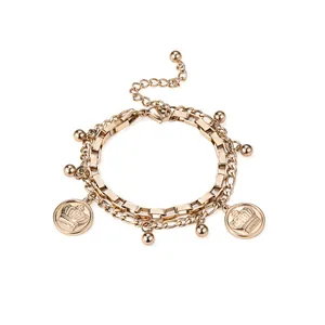 Bracelet double rang en acier titane doré avec breloques couronne et billes polies.