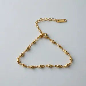 Detailed view of a golden stainless steel bead chain bracelet with lobster clasp