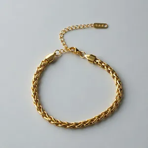 Close-up detail of a gold braided stainless steel wheat chain bracelet with lobster clasp.